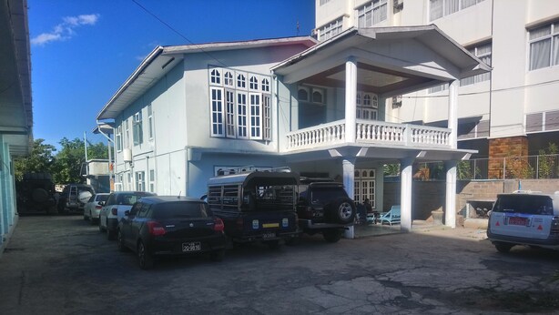 A multi-story building with a covered parking area. - Diamond Star Guest House (Nyaungshwe)
