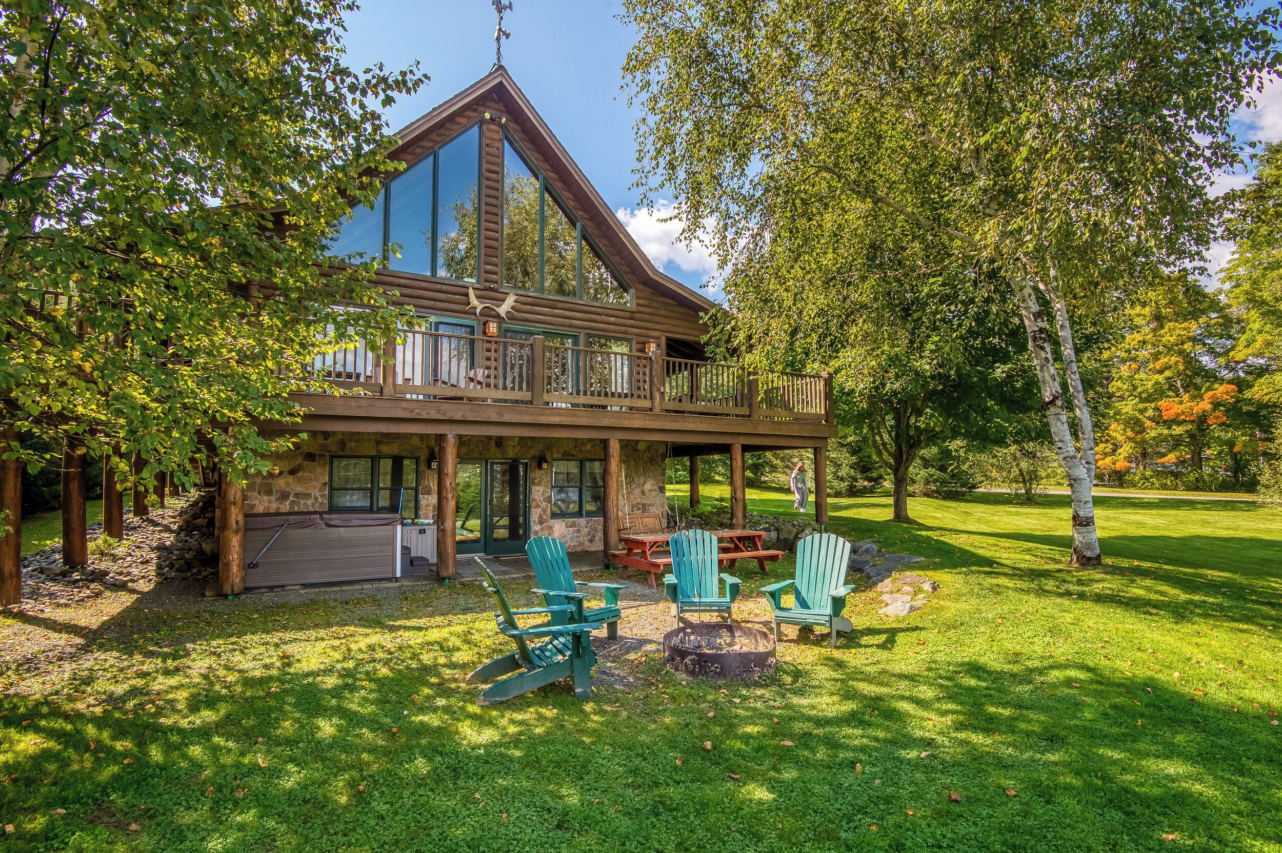 Een lodge met een ruim terras, buitenmeubels en een gevel van natuursteen.