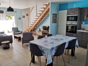 A modern living space with a dining area, kitchen, and a staircase.