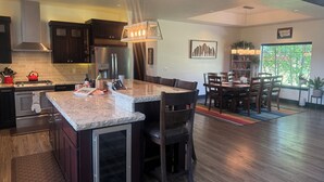 A modern kitchen with dark wood cabinets, stainless steel appliances, and a marble countertop. - Country setting close to Glacier National Park (Columbia Falls)