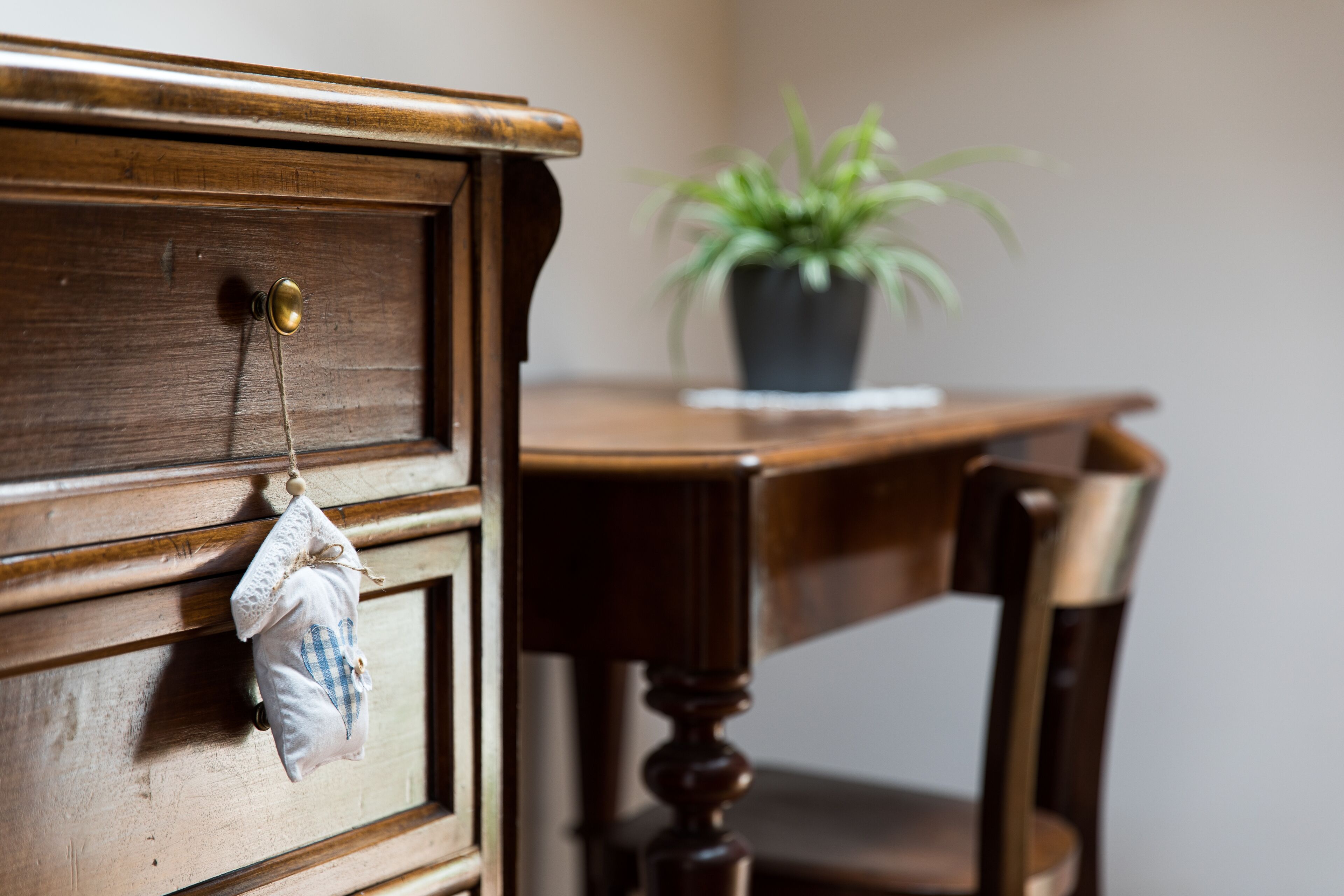 A wooden dresser with a brass handle and a small cloth bag hanging from it.
