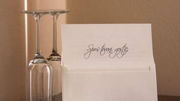 A table with two wine glasses, a small glass bowl, and a white card with cursive writing.