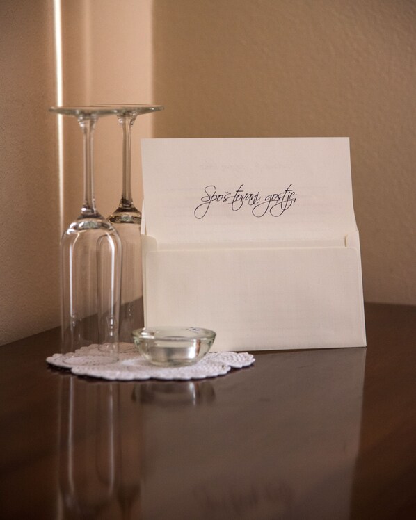 A table with two wine glasses, a small glass bowl, and a white card with cursive writing.