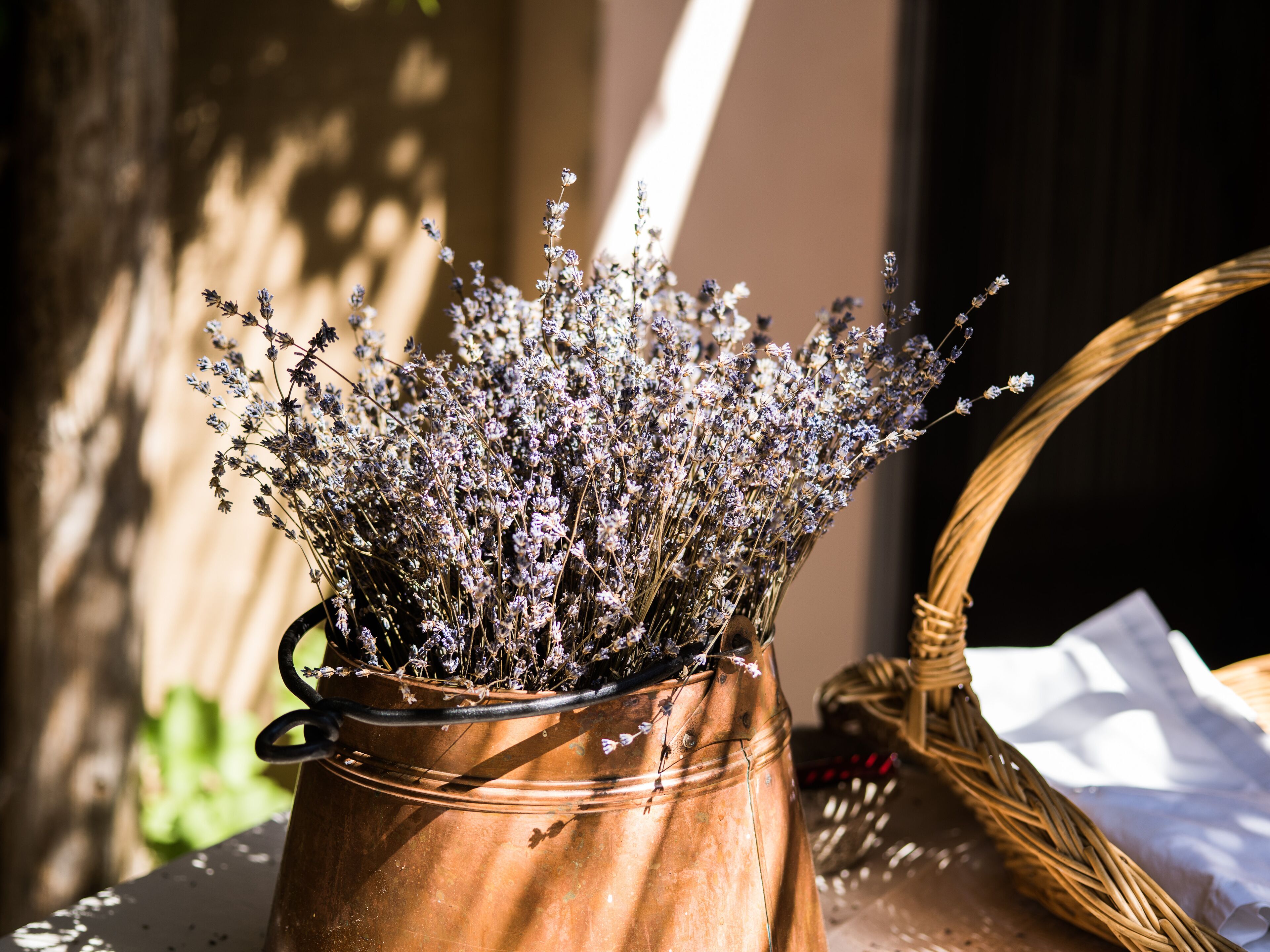 Um vaso de cobre com raminhos de lavanda seca sobre uma mesa.