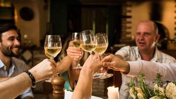 Un grupo de personas brindando con copas de vino en una mesa con vela y flores.