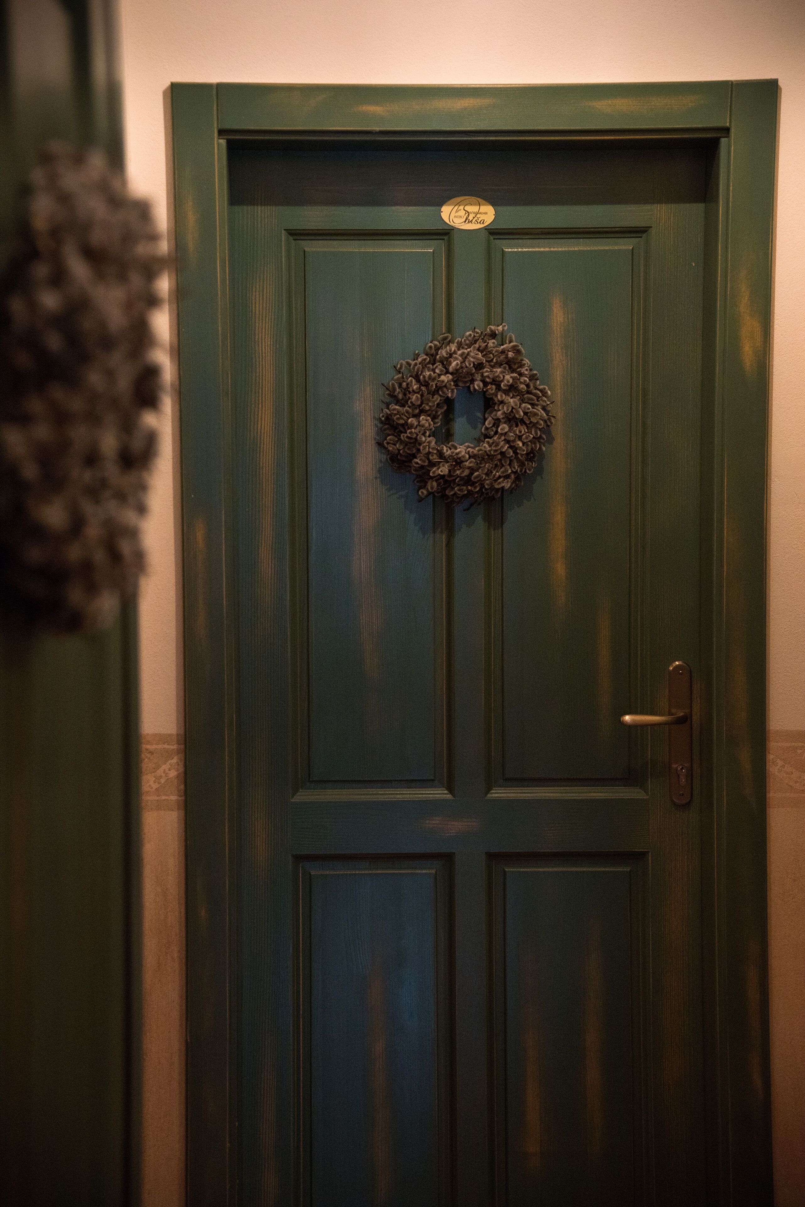 A green door with a wreath and a brass plate.