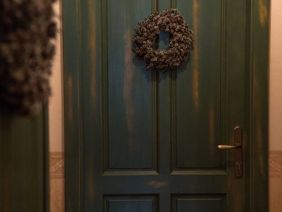 A green door with a wreath and a brass plate.