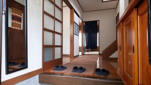 A traditional Japanese interior with sliding doors, a wooden floor, and a set of black slippers on a mat.