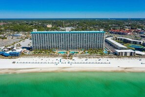 Un hotel grande con varios pisos, ubicación frente a la playa y zona de piscina.