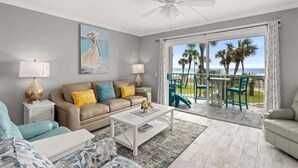 A living room with a sofa, coffee table, and a view of the outdoors through a sliding glass door.
