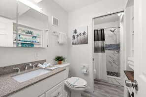 Un baño moderno con lavamanos de granito, inodoro y zona de ducha.