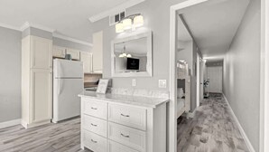 A modern kitchen with white cabinetry, a marble countertop, and a built-in oven.