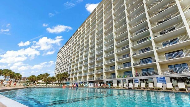 A hotel with a large pool and multiple balconies.