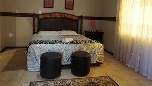 A bedroom with a bed, two wall-mounted pictures, a nightstand, and a window with curtains. - Times Premier Lodge (Vryburg)