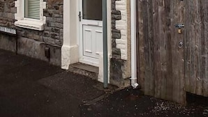Un edificio in pietra con una porta bianca e finestre, una recinzione in legno e un cartello sulla porta.