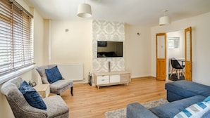 A living room with a sofa, armchairs, a TV, and a wooden cabinet. - Twyn Lodge - 3 Bed House (Pontlliw)