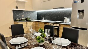 A modern kitchen with marble countertops, wooden cabinets, and a built-in water dispenser. - Tourists Residence (Vlorë)