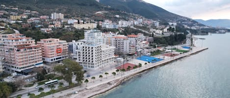 A coastal cityscape with residential buildings, a beach, and a mountainous backdrop.