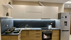 A modern kitchen with a black marble backsplash, wooden cabinets, a stainless steel sink, and a built-in oven. - Tourists Residence (Vlorë)