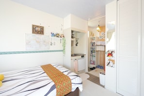 A bedroom with a bed, a desk, and a wardrobe.