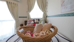 A room with a wicker basket filled with towels, a bed with striped bedding, and a wall map. - 1 # Disneyland 6 minutes / To Tokyo Station 13 minutes / wifi / 24 hour supermarket nearby / (浦安市)