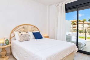 Un dormitorio con cama, mesita de noche, lámpara y vistas al exterior.