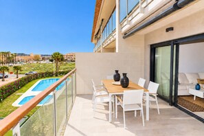 Un balcón con piscina, mobiliario blanco y vistas del entorno.