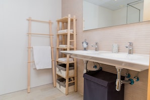 Un baño con un perchero de madera, un lavabo blanco y un espejo encima.