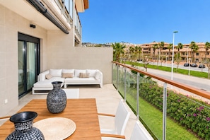 A balcony with a white sofa, a wooden table, and a vase. - Altamar Plus Apartment Javea Arenal, Stylish with AC, Wifi, Terrace and Pool (Javea / Xàbia)