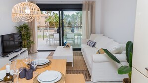 A modern living room with a sofa, coffee table, and dining table set for a meal. - Altamar Plus Apartment Javea Arenal, Stylish with AC, Wifi, Terrace and Pool (Javea / Xàbia)