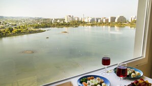 A table with plates of sushi and two glasses of red wine, a window overlooking a river with buildings in the background. - Romantic loft for couples with views of the ocean, the salt flats, and the natural park (Calpe)