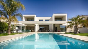Una casa moderna de dues plantes amb una piscina al primer pla.