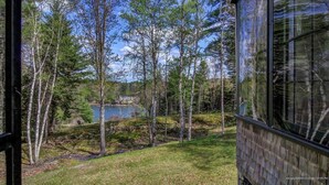 A view from a window overlooking a lake surrounded by trees, with a building visible in the foreground. - Doggett Castle Guest House (Westport)