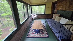 A room with a wooden ceiling, large windows, a bed, a chair, and a table with a patterned rug. - Doggett Castle Guest House (Westport)