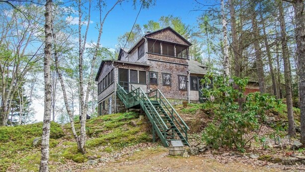 A rustic cabin with a brick exterior, a green staircase leading to the entrance, surrounded by a forested area. - Doggett Castle Guest House (Westport)