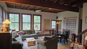 A cozy living room with a wooden ceiling, a dining table, and a sofa. - Doggett Castle Guest House (Westport)