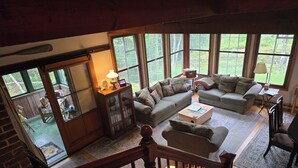 A spacious living room with a large window, a wooden bookshelf, and a cozy seating area. - Doggett Castle Guest House (Westport)