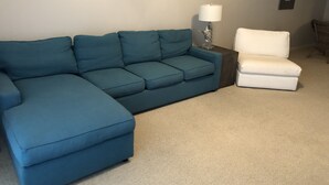 A living room with a blue sectional sofa, a white armchair, and a small side table with a lamp. - Great 3Br/2Ba Waterfront Condo in OBA near Perdido Pass (Orange Beach)