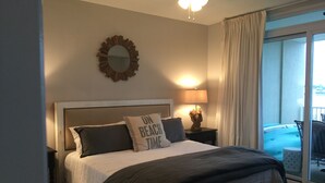 A bedroom with a bed, a nightstand, a lamp, a mirror, and a view of a balcony. - Great 3Br/2Ba Waterfront Condo in OBA near Perdido Pass (Orange Beach)