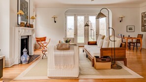 A spacious living room with a fireplace, a sofa, a coffee table, and a dining area. - Elegant Watefront home with Oversized Gunite Heated Pool, Tennis, Living... (Water Mill)