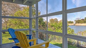 A covered porch with a view of a lake and trees. - Elegant Watefront home with Oversized Gunite Heated Pool, Tennis, Living... (Water Mill)