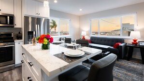 A modern kitchen with a large island, stainless steel appliances, and a view of the sunset through large windows. - 1stResorts.com 3NEW FAMILY VILLAS/AMAZING WATER VIEWS/AC/3 decks/3hottubs/parkng (San Diego)