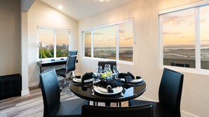 A dining area with a table set for four, large windows with a city view, and a chandelier. - 1stResorts.com 3NEW FAMILY VILLAS/AMAZING WATER VIEWS/AC/3 decks/3hottubs/parkng (San Diego)