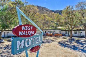 A motel sign with 'WEST WALKER' and 'MOTEL' text, a dirt ground, and a building with a flat roof in the background.