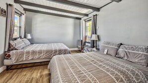 A room with two beds, a wooden floor, and a sloped ceiling with exposed beams. - WWM 5 · 5 Swim, fish, hike++ the Eastern Sierras WWM 5 (Coleville)
