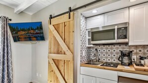 A kitchen with a wooden barn door, white cabinets, a microwave, and a coffee maker.