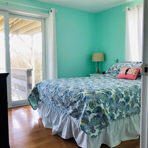 Un dormitorio con una cama, una mesita de noche, una lámpara y una ventana con cortinas.