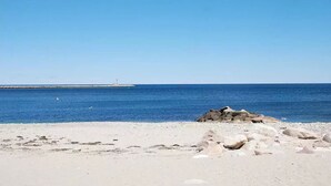 Una playa con primer plano rocoso y cielo azul despejado.