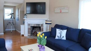 Una sala de estar con chimenea, televisor montado, telescopio y decoración temática náutica.