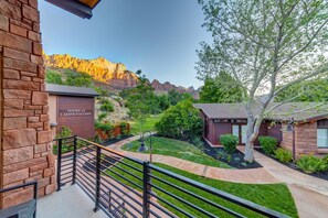 A residential area with stone and wooden buildings, a well-maintained lawn, and a mountain backdrop. - LaFave-Luxury Villa at Zion: Echo Canyon (Springdale)